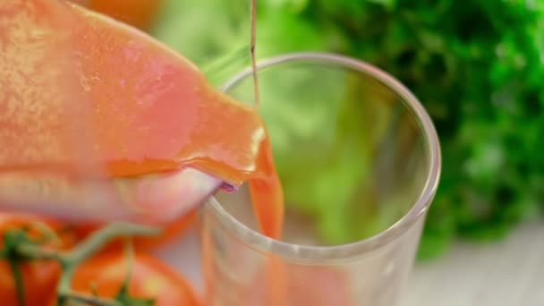 Tomatjuice med kvist tomater på bakgrunden. Tomatjuice hälls i ett glas. slow motion — Stockvideo