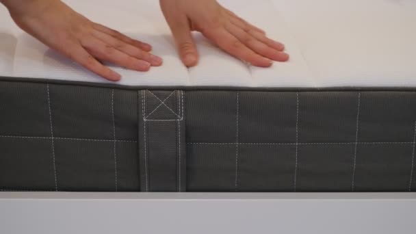 De vrouw kiest een nieuwe matras om goed te slapen. De hand van de vrouw test de matraskwaliteit. Ik controleer zachtheid. Keuze van de beste soort en kwaliteit. Zijaanzicht. Sluitingsdatum. — Stockvideo