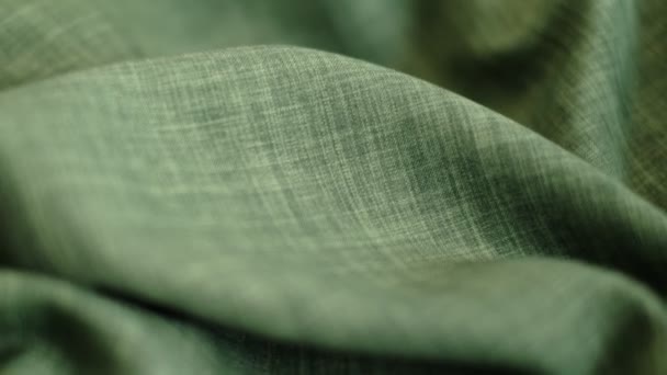 Closeup the motion footage vide. green linen textile abstract background. Clothing industry concept. Wavy material. velours fabric threads macro. Side view. Close-up shooting stock footage — Vídeo de Stock