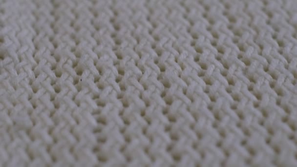 Detailní záběry z pohybu. Textilní abstraktní pozadí. Koncept oděvního průmyslu. Vlnitý čistý materiál. Vlákna pletených šatů s bílými nitěmi. Makro pletené textilie. — Stock video