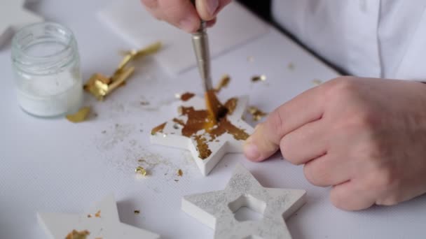 Die Anwendung von Blattgold. Künstlerin dekoriert goldenes Gips-Handwerk mit einem Blatt Gold. — Stockvideo