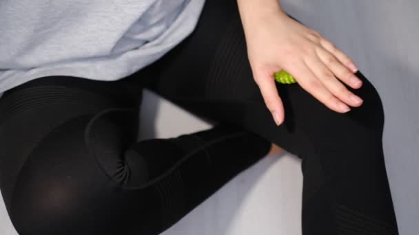 Close-up a young woman in a short topic is working out the hip muscles with a green myofascial ball — Stock Video