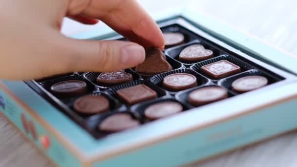 Woman take one chocolate from a box of different candies. Close-up shooting stock footage. — стоковое видео