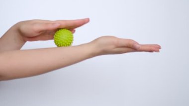 Close-up a young woman working out the arm muscles with a green myofascial ball. Woman doing exercises with rubber ball, closeup.