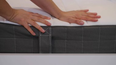 Kadın iyi bir uyku için yeni bir yatak seçiyor. Kadının eli yatak kalitesini test ediyor. Yumuşaklığı kontrol ediyorum. En iyi tip ve kalitede bir seçim. Yan görüş. Yakın çekim..