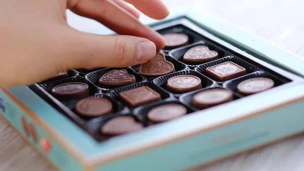 Kadın, bir kutu farklı şekerden bir çikolata alır. Yakın plan. Kalp şeklinde şeker, sevgililer günü — Stok fotoğraf