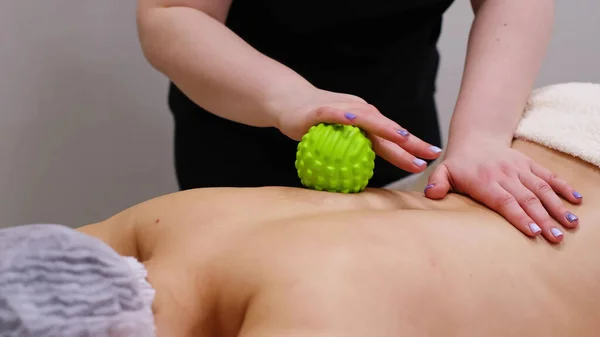 Woman at the physiotherapy receiving ball massage from therapist. A chiropractor heals the patients back in medical office. Neurology, Osteopathy, chiropractic