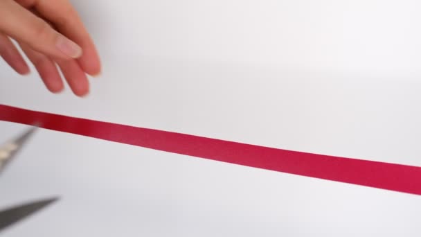 Рука с ножницами, перерезающая красную ленточку, концепция церемонии открытия. Изолированный на белом фоне — стоковое видео
