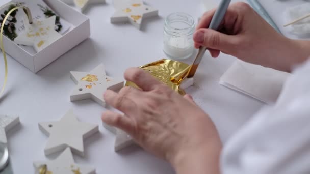 Применяю Золотой лист. Женщина художник украшает золотой штукатуркой ремесло с листом золота. — стоковое видео