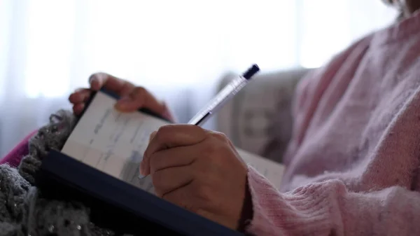 Unrecognizable woman in warm knitted sweater writes down plans or tasks for the new year. — Stock Photo, Image