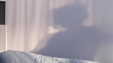 Duvardaki gölgelerle oynayan küçük bir çocuk. Duvara yansıyan dans eden bir çocuğun gölgesi, bulanık siluet