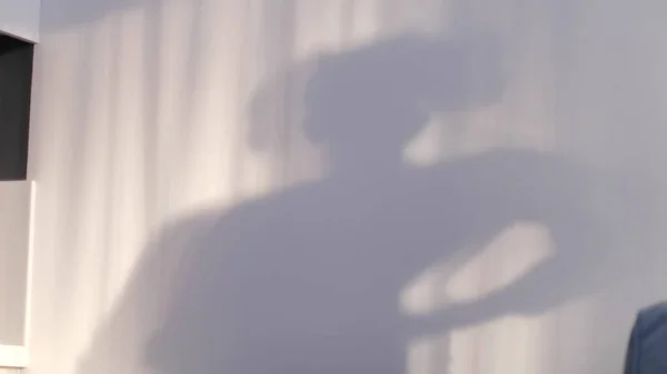 Sfoca il bambino che gioca con le ombre sul muro. ombra di un ragazzo danzante riflessa sul muro, silhouette sfocata — Foto Stock