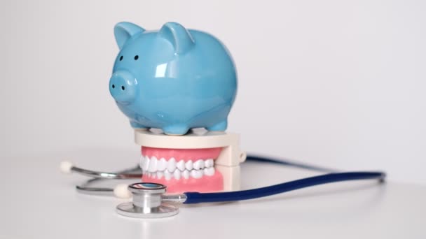 Piggy banco com dentes brancos modelo no fundo branco. conceito de compensação fiscal. Deduções de Despesas Médicas e Rupturas Fiscais. ato de cuidado acessível. cuidados de saúde de alto custo. despesas dentárias — Vídeo de Stock