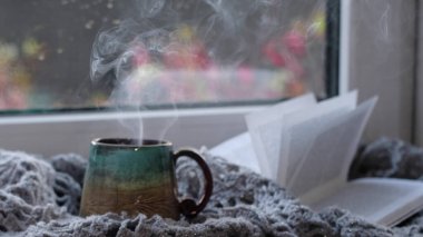 Yağmurlu bir arkaplanda buharlı kahve fincanı. Sıcak atmosfer, soğuk havada. Yağmurlu bir gün. sıcak ev atmosferi