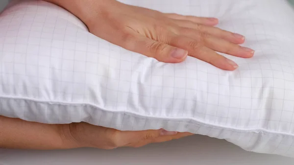 Giovane donna toccando morbido cuscino bianco, primo piano. come scegliere un cuscino, riempimento artificiale — Foto Stock