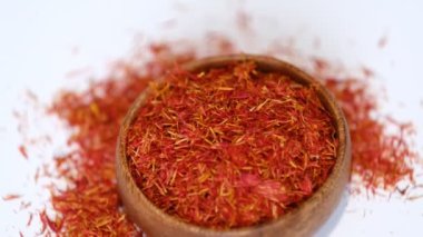 Ahşap safran kasesi kendi etrafında dönüyor. Ahşap tabakta beyaz arka planda izole edilmiş safran iplik. Stok görüntüleri. yavaş çekim.