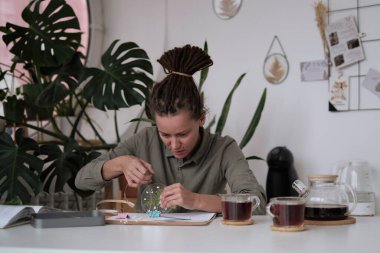 Kadın cam levhaları tamir ediyor. Kurumuş çiçek resmi. Çerçeve yaratma konusunda yüksek sınıf. Yaratıcılıkla daha ilgili ol. Mutluluk ve Tamamlanma Hayatı