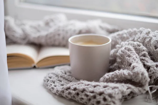 Casa accogliente con una tazza di caffè e un libro. Stile Hygge. Tazza di caffè nero avvolto in calda sciarpa su tavola di legno. Vista dall'alto, stile vintage, Natura morta . — Foto Stock