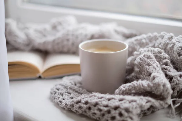 Acogedora casa con una taza de café y un libro. Estilo Hygge. Taza de café negro envuelto en pañuelo caliente sobre tabla de madera. Vista superior, estilo vintage, Naturaleza muerta . — Foto de Stock