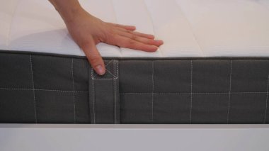 Kadın iyi bir uyku için yeni bir yatak seçiyor. Kadının eli yatak kalitesini test ediyor. Yumuşaklığı kontrol ediyorum. En iyi tip ve kalitede bir seçim. Yan görüş. Yakın çekim..
