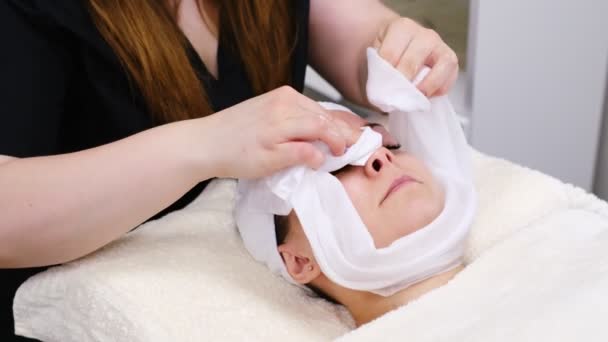 Mladá žena ležící na nosítkách v estetickém centru provádějící kosmetické ošetření a obličejovou estetiku — Stock video