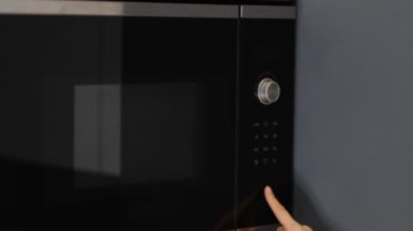 Kadın elleri modern mikrodalga fırında bir kap yemeği ısıtıyor. Evde atıştırmalık yemek için.