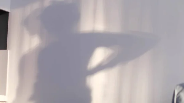 Sfoca il bambino che gioca con le ombre sul muro. ombra di un ragazzo danzante riflessa sul muro, silhouette sfocata — Foto Stock