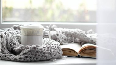 Bir fincan kahve ve bir kitapla rahat bir ev. Hygge tarzı. Tahta tahtada sıcak atkı ile sarılmış siyah kahve bardağı. Üst görünüm, vintage tarzı, Natürmort.