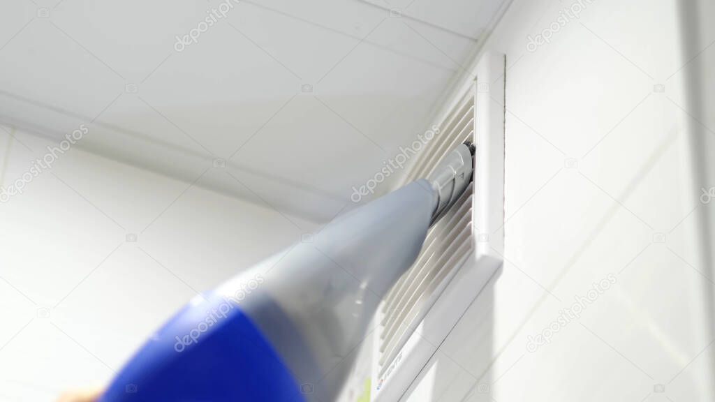 Closeup of vacuum cleaner pipe and ventilation grill. ventilation grill in the bathroom. cleaning hard-to-reach places.