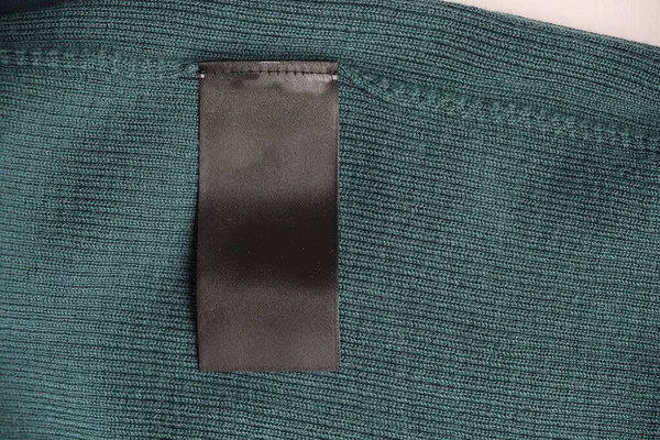 Etiqueta de ropa de lavado negro en blanco sobre fondo de textura de tela verde. lana merino natural. — Foto de Stock