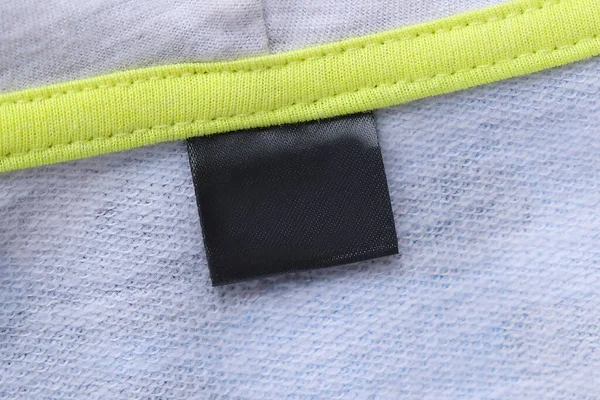 Etiqueta de ropa de lavado negro en blanco sobre fondo de textura de tela gris. —  Fotos de Stock