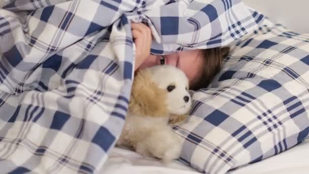 Парень прячется под одеялом, подглядывает. игривый ребенок не хочет вставать с кровати — стоковое видео