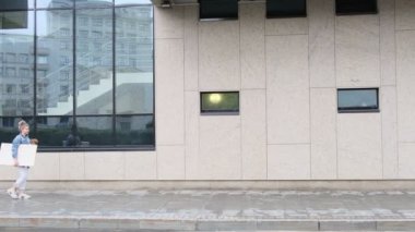 Genç modern kadın sanatçı elinde büyük bir tabloyla yürüyor, küçük köpeği de onunla yürüyor.