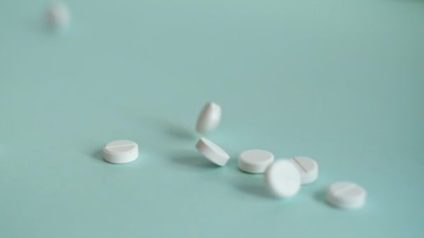 Weiße Pillen, die in Zeitlupe auf blauen Hintergrund fallen. Tabletten fliegen. medizinisches Filmmaterial, gesunder Lebensstil, Vitamine, Medikamente — Stockvideo