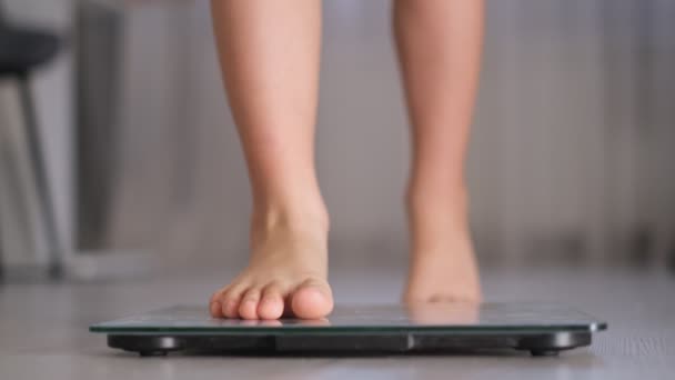 Child measuring weight. Weight control concept with centimeter in focus and blurred kids feet on digital scale. — Stock Video