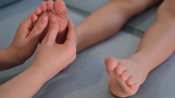 Mama robi masaż na stopie dziecka. Zapobieganie płaskie stopy, rozwój, napięcie mięśni, dysplazja. Wyszkolony reumatolog leczący stopy pacjentów. Masażysta masujący stopy dla dzieci. — Wideo stockowe