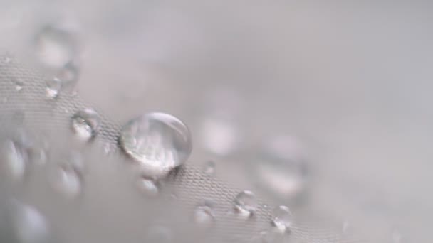 Wasserspritzer in Zeitlupe auf wasserdichtem Gewebe. Wasserperlen auf Stoff. Wasserdichte Beschichtung Hintergrund mit Wassertropfen. Weicher Fokus, Unschärfe — Stockvideo