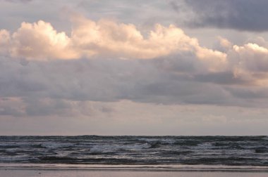 Japon denizi ve batan güneşte yıkanan bulutlar.