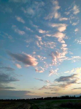 Sarı ufuk çizgisini kaplayan gökyüzünün görüntüsü ve gökyüzü mavi gökyüzünde yüksek beyaz bulutlar