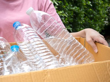 Geri dönüşüm için plastik şişe çöpü kutusunu tutan kadın, çevre kavramsal.
