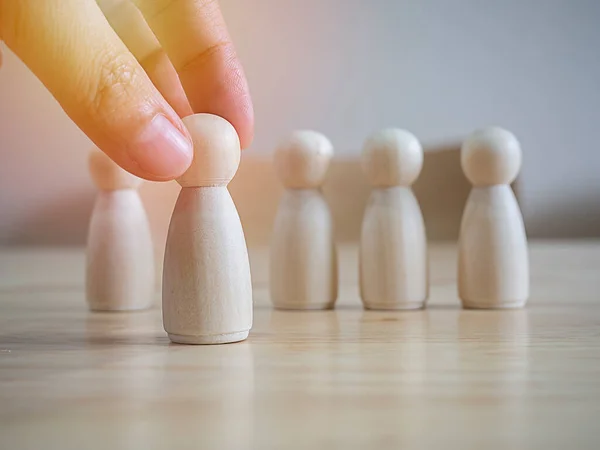 Hand choose a wooden figure to in front of line with each other figure and show different thinking ideas. Leadership and disruption for new normal concept.