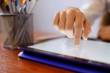 Sınıfta üstü açık laptop kullanan genç bir öğrenci. İlkokuldaki teknolojileri kullanarak.