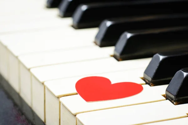 Red heart on a keys of a keyboard of an classic old piano. Concept of love, romantic mood