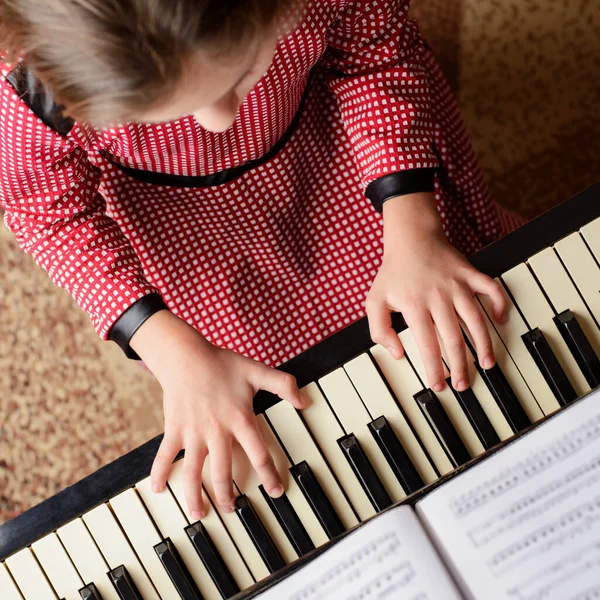 Little girl learning to play the piano at home