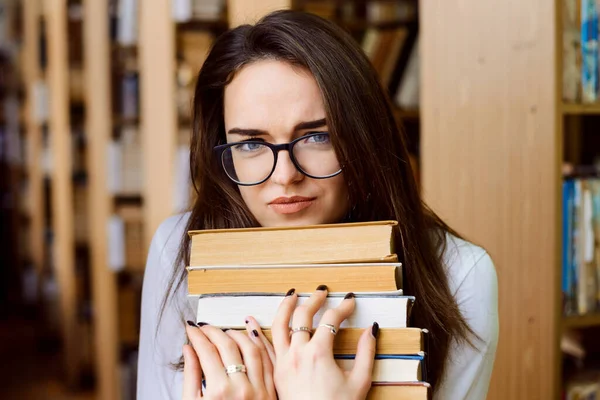 多くの本を持つ図書館で疲れて女性学生試験のために準備 — ストック写真