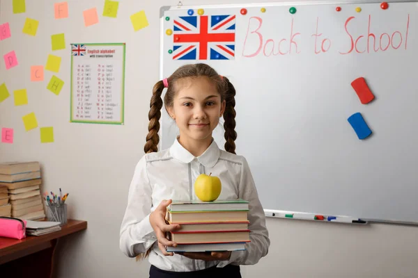 English female student with books in her hands and British flag at the background