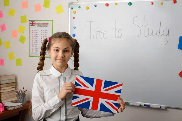 English learner of secondary school holds Union Jack flag standing in classroom of conventional school