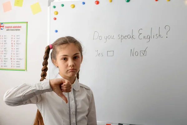 Young learner has bad knowledge of English. Unhappy pupil of secondary school showing thumbs down gesture. Concept of international language, lack of knowledge of English