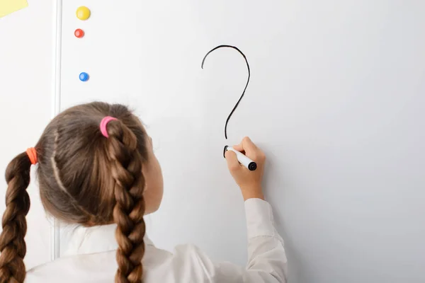 Schoolgirl writing big question mark on the blackboard. Concept of difficult question, curiosity, studying, developing, asking questions