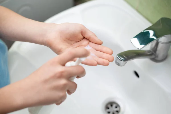 Washing hands with liquid soap in bathroom